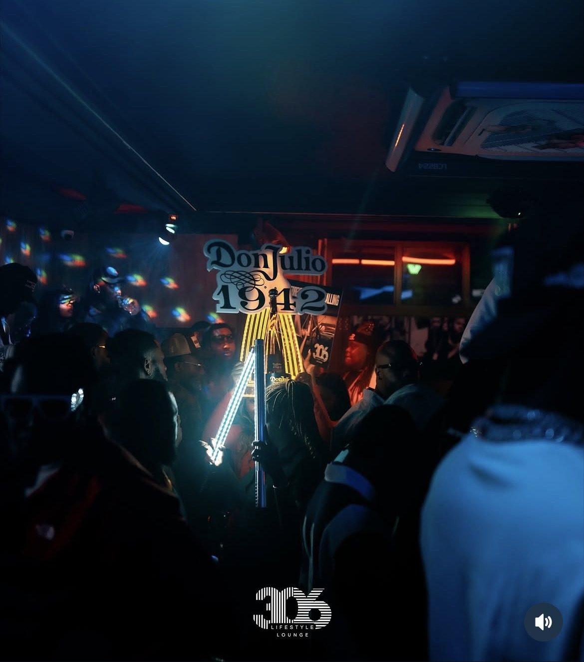 Crowd celebrating with a lit Don Julio 1942 bottle presentation